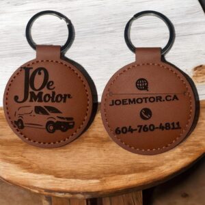 a faux leather circle shape keychain with a car engraved on
